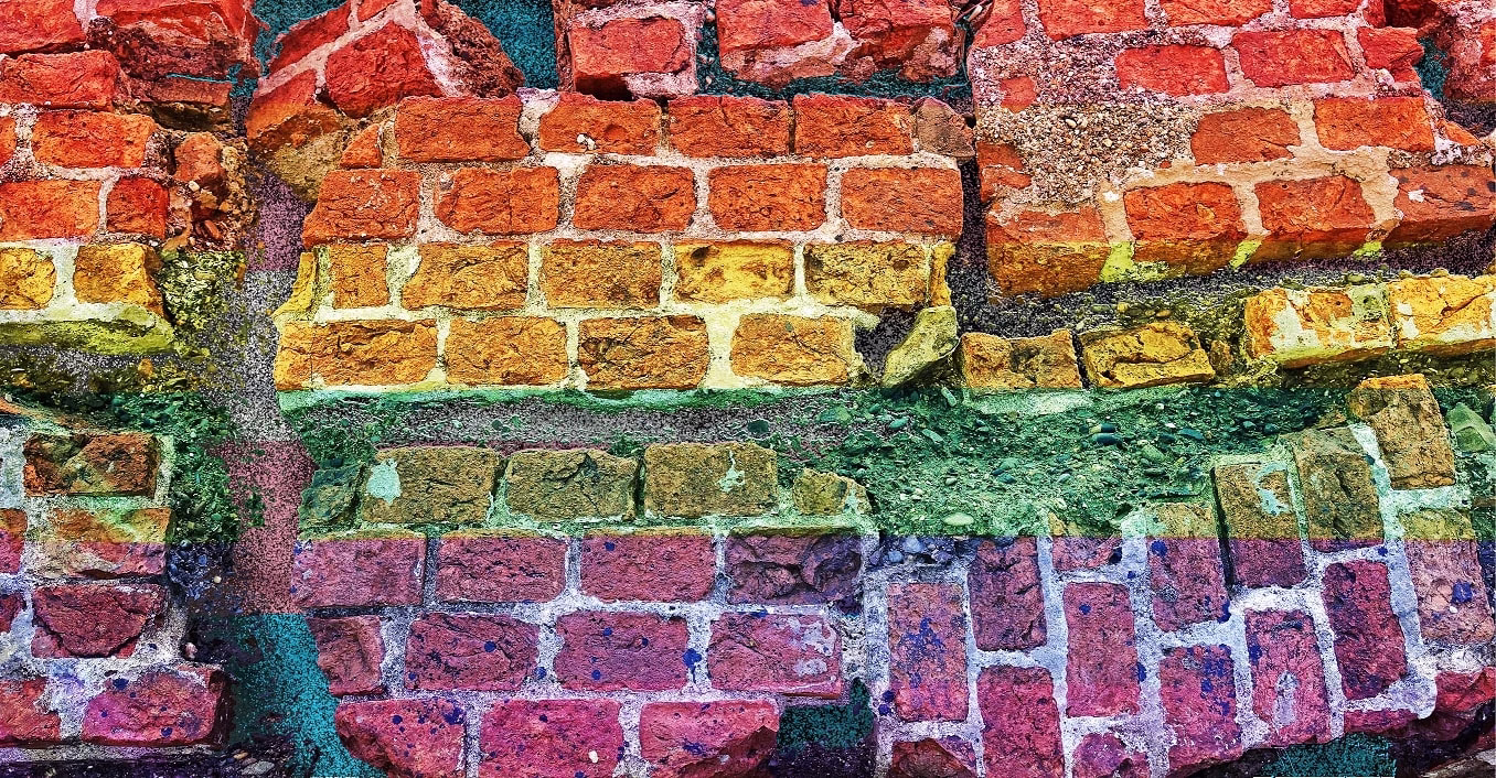 Broken rainbow coloured stonewall with a transgender flag showing through the cracks